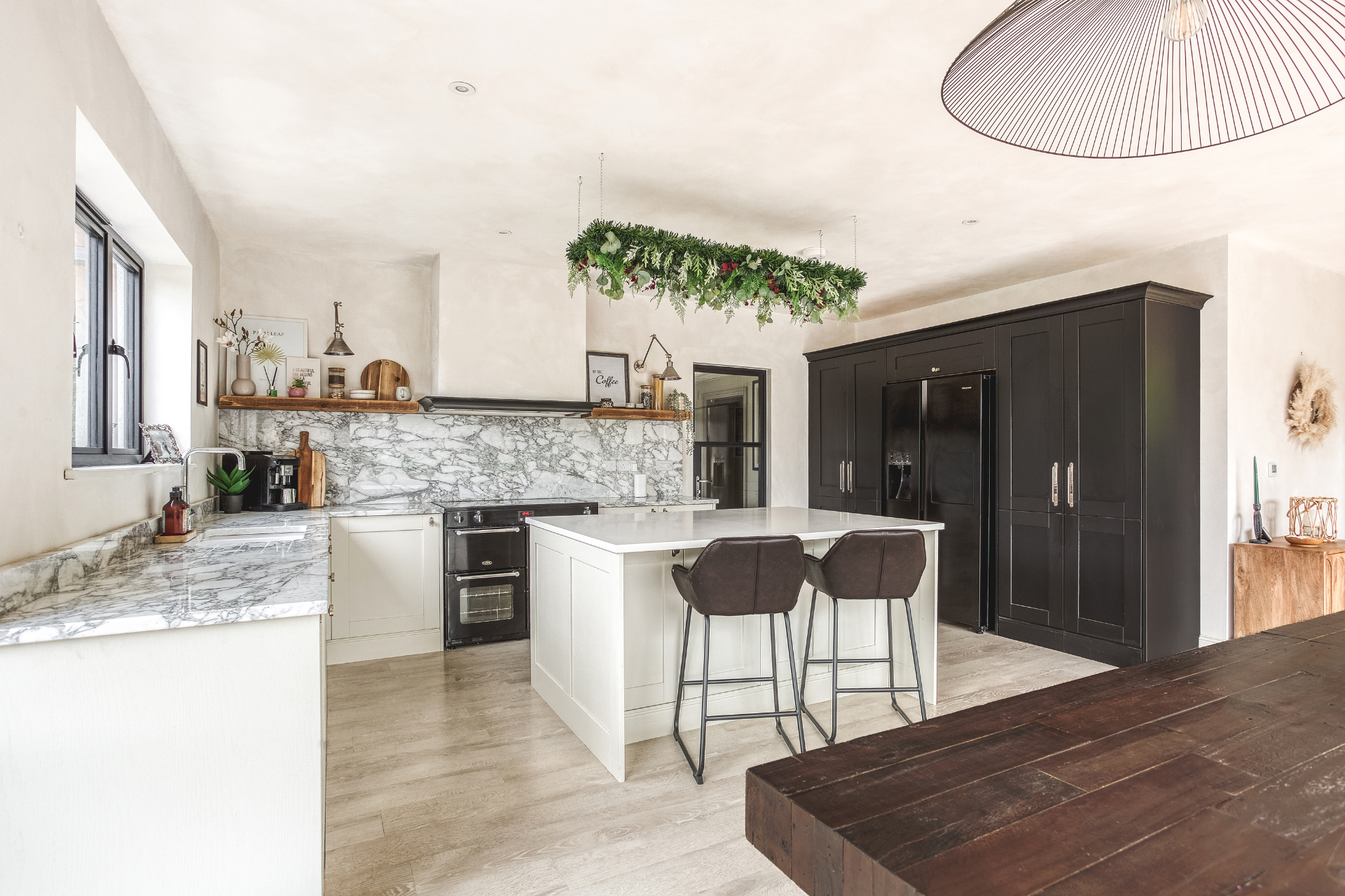 Spacious kitchen with marble worktops, white island and dark cabinetry