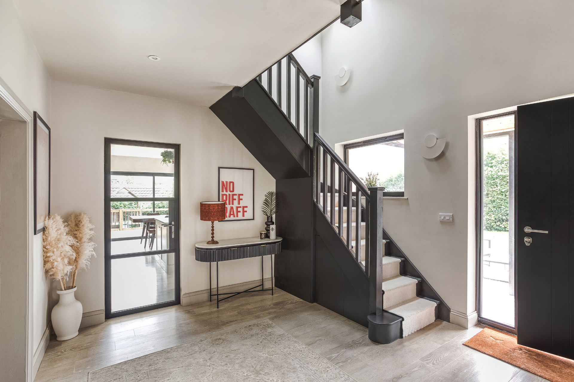 Entrance hall with dark staircase, glazed internal door and contemporary finishes