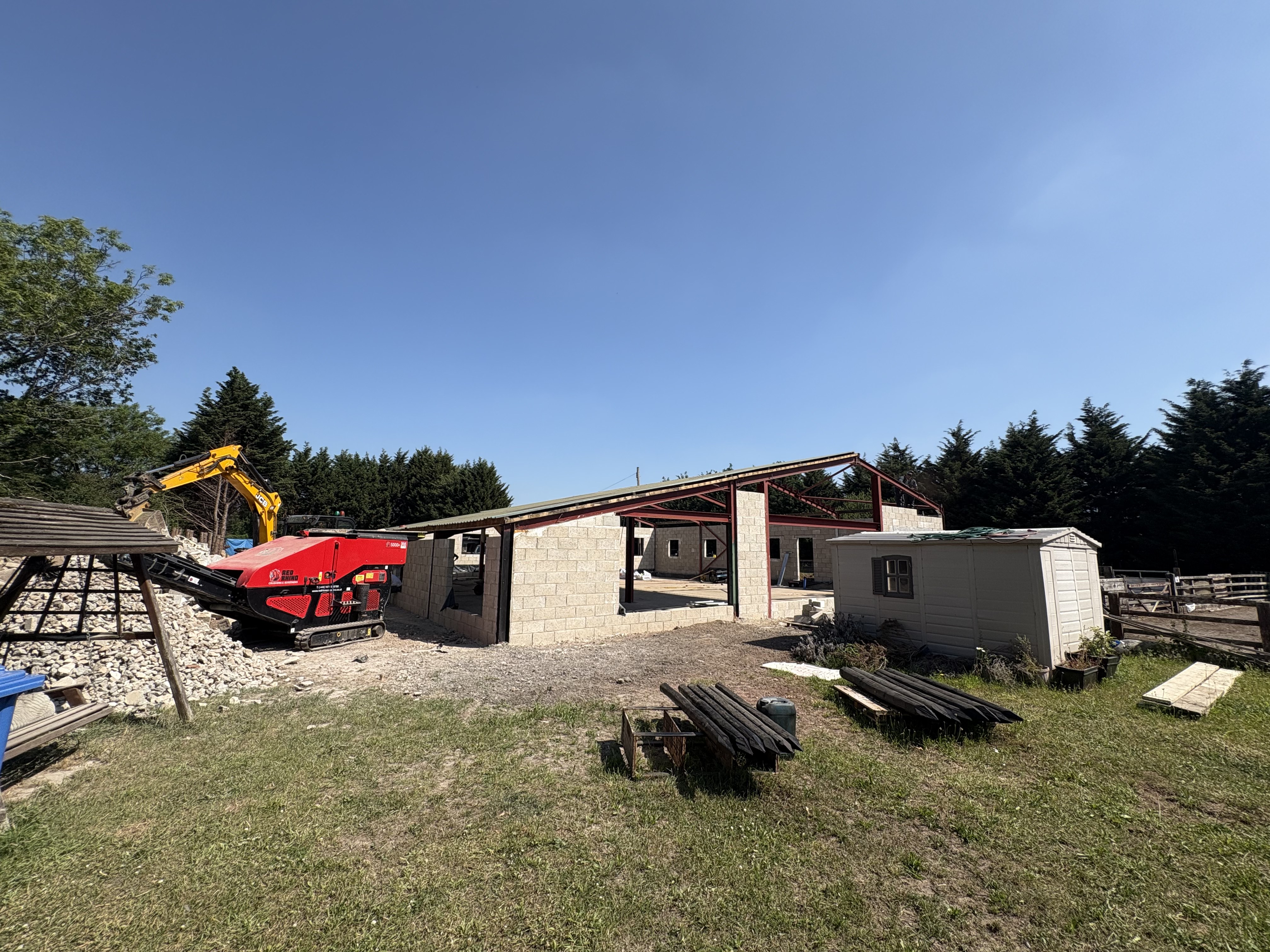 Barn conversion progress — long elevation of the new blockwork enclosure under the retained profiled steel roof