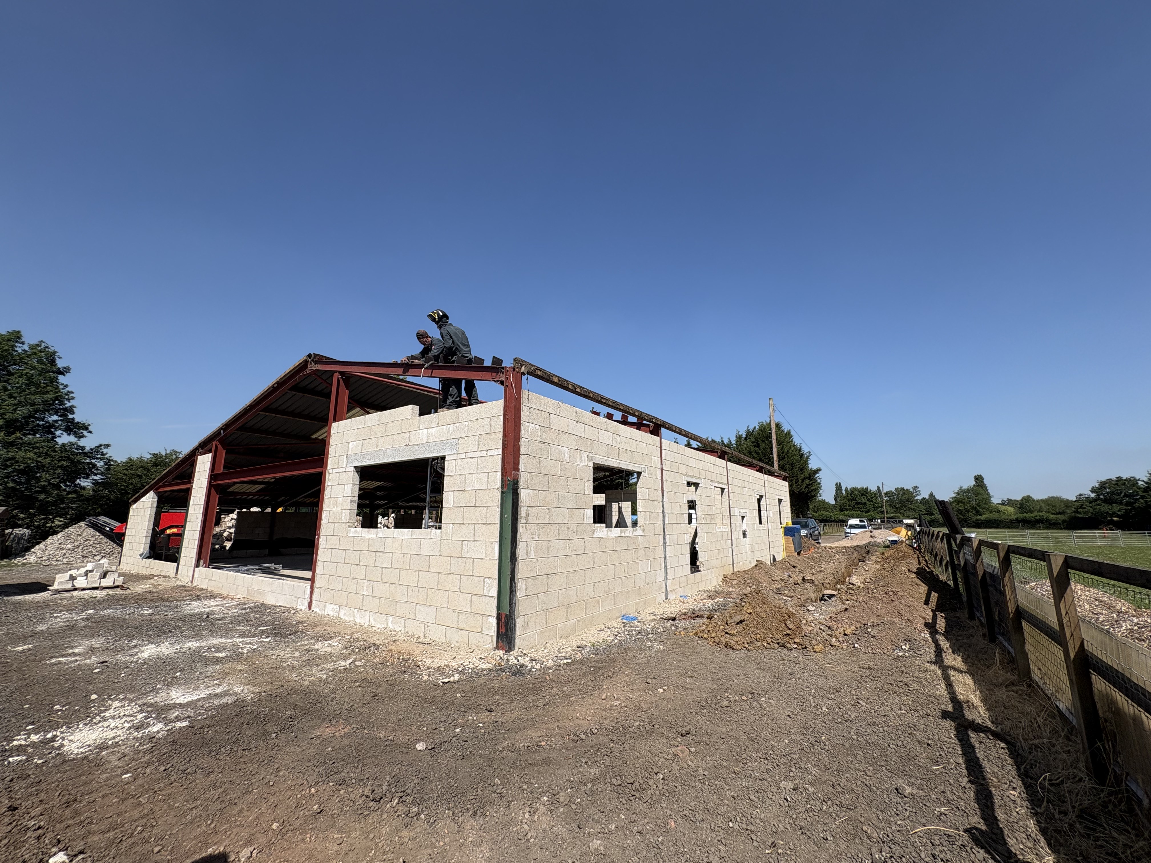Wide interior shot of the barn shell during Class Q conversion, with new openings cut into the blockwork walls
