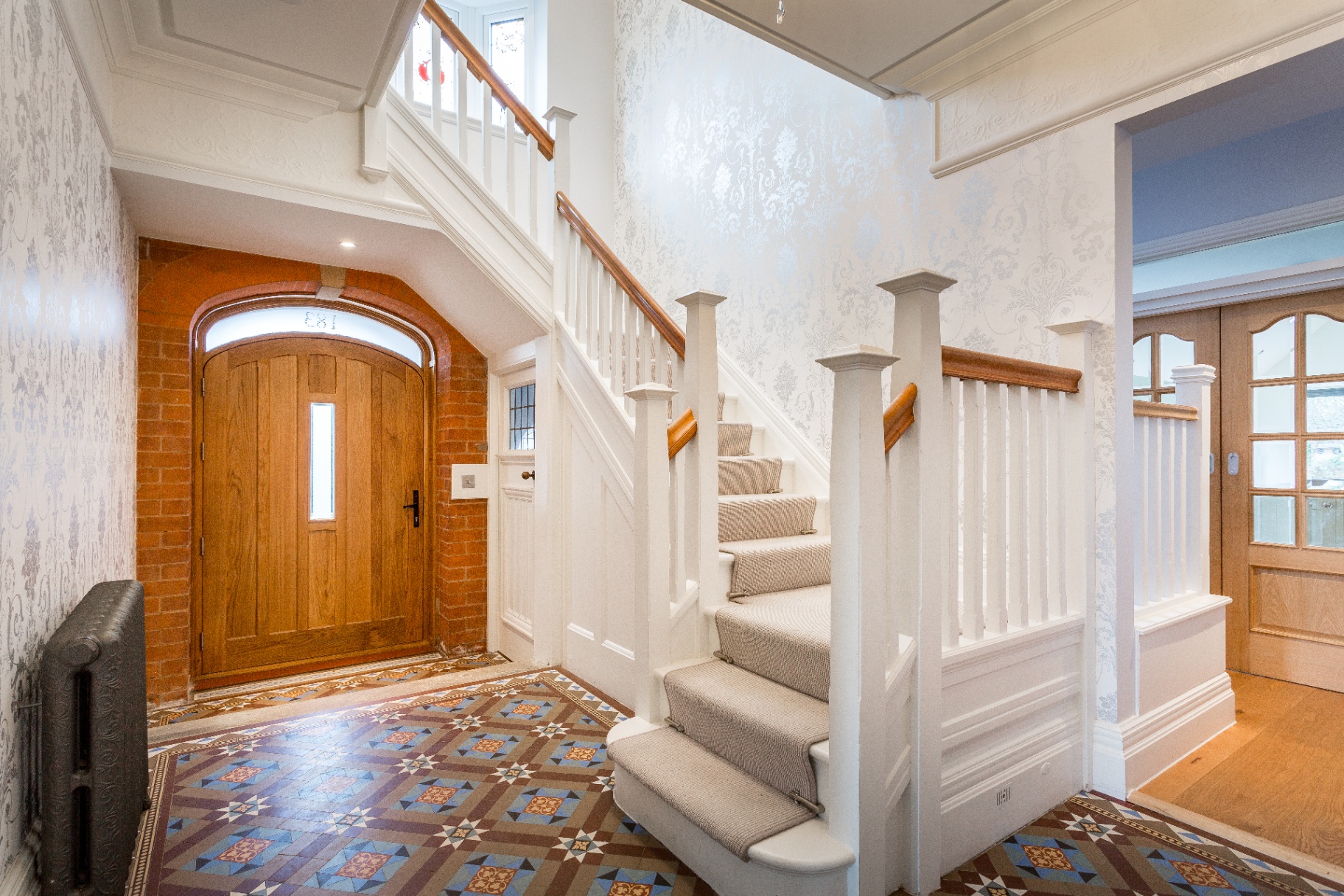 Restored entrance hallway with original mosaic tiled floor and oak staircase