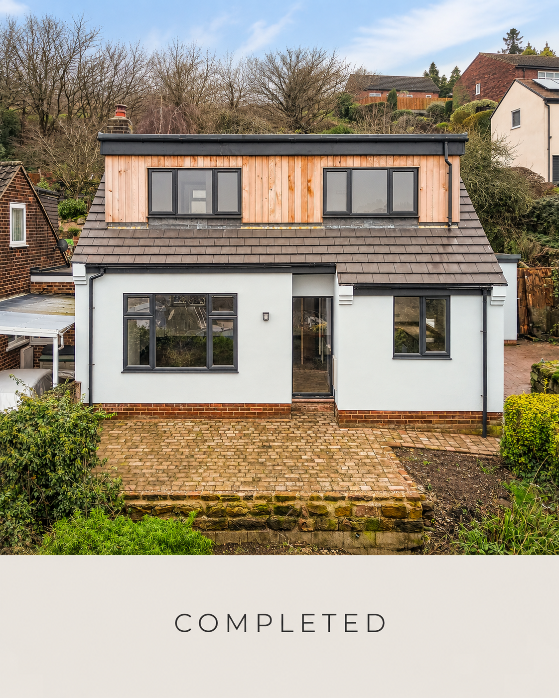 The finished home: a contemporary dormer extension with crisp white render, dark detailing and natural timber cladding