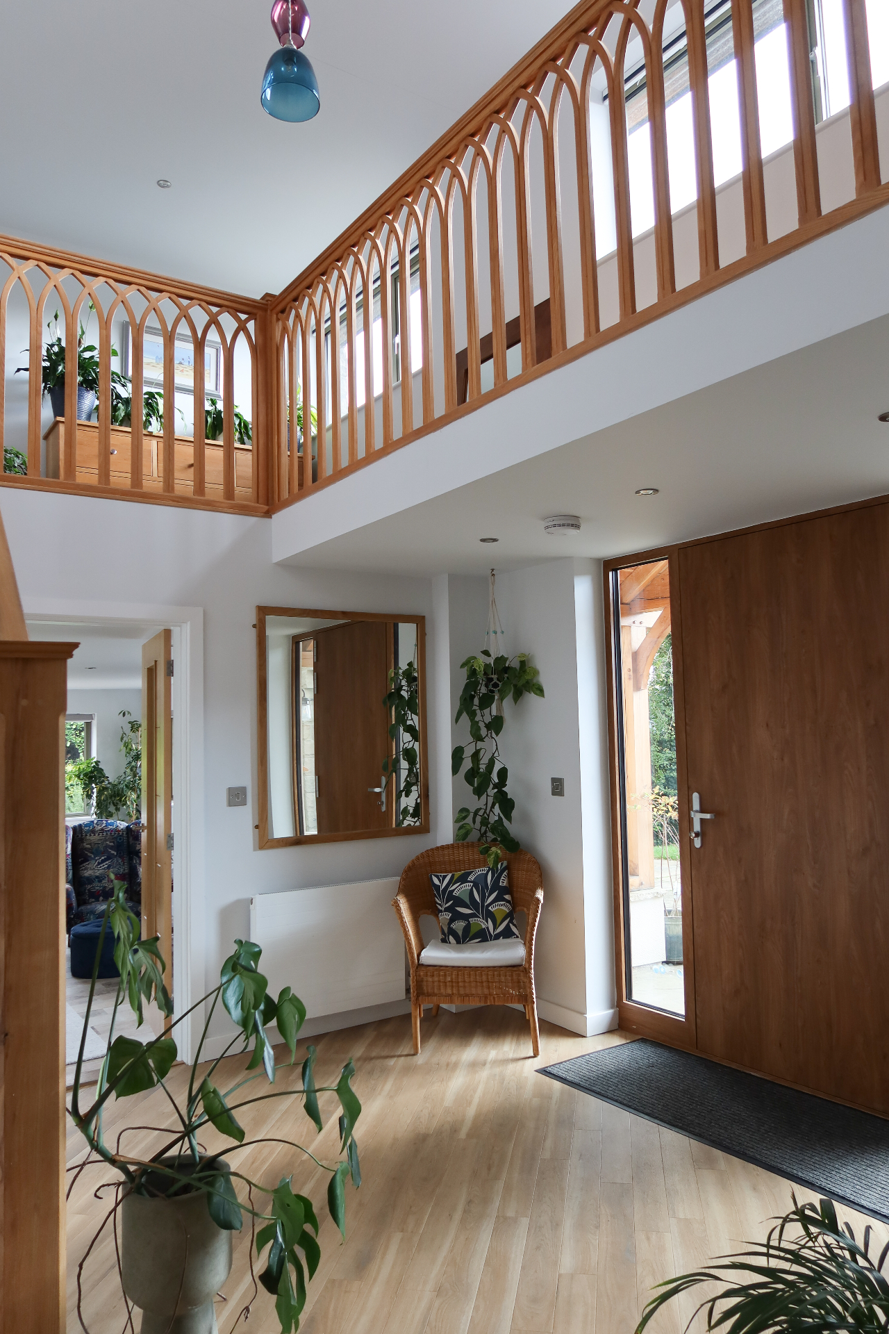 Double-height entrance hall with bespoke timber gallery railing and oak front door