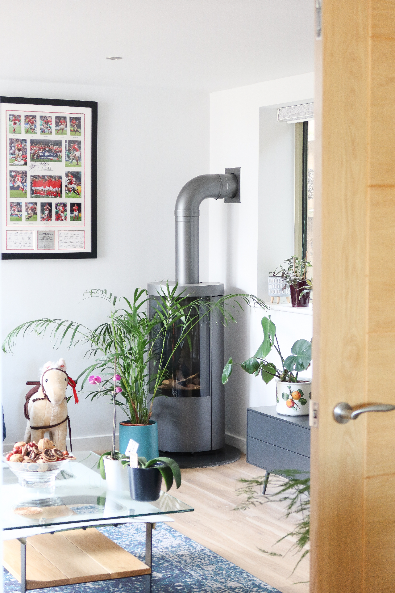 Snug lounge with contemporary cylindrical woodburning stove and timber flooring