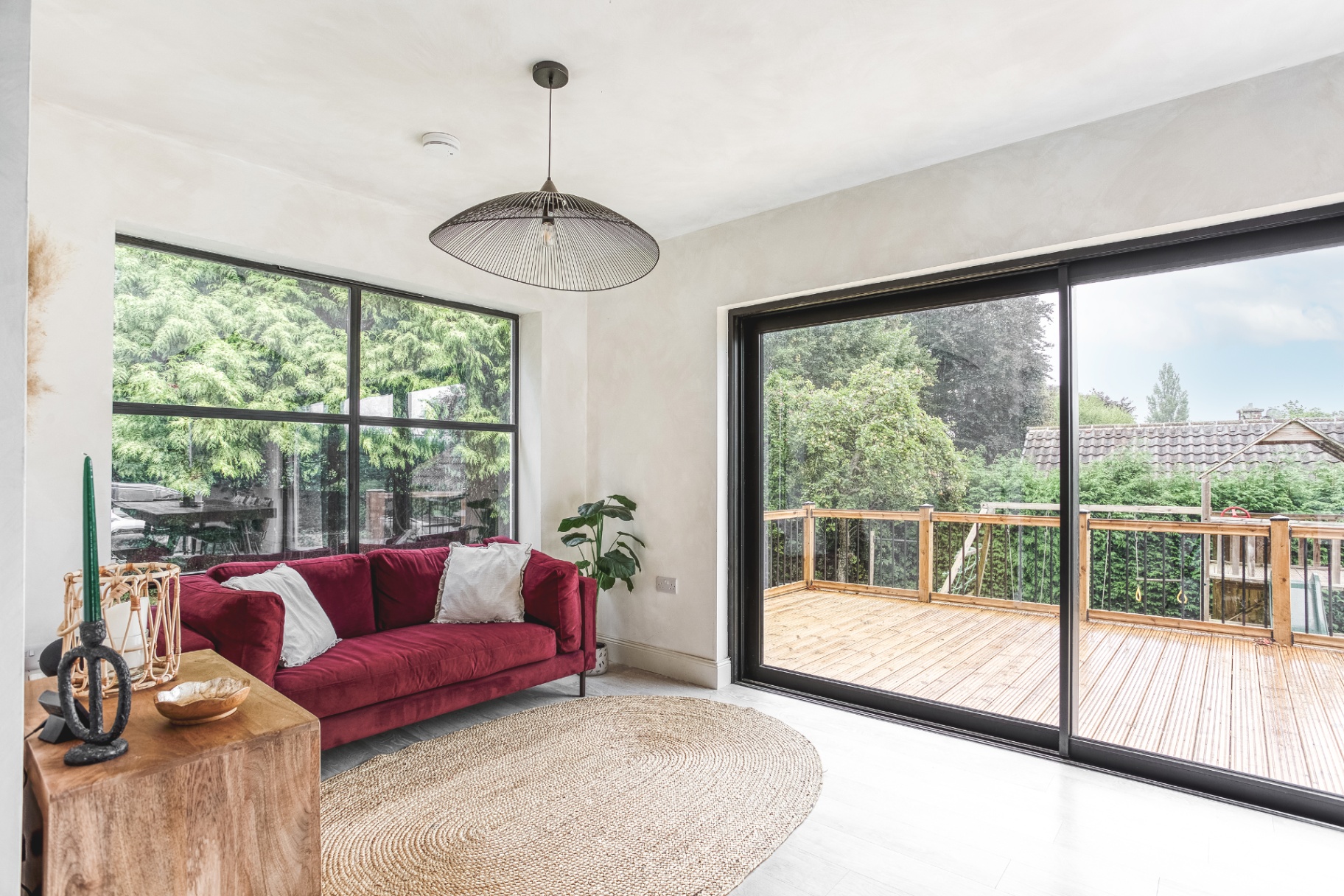 Upper lounge area opening onto a timber balcony deck through large sliding doors